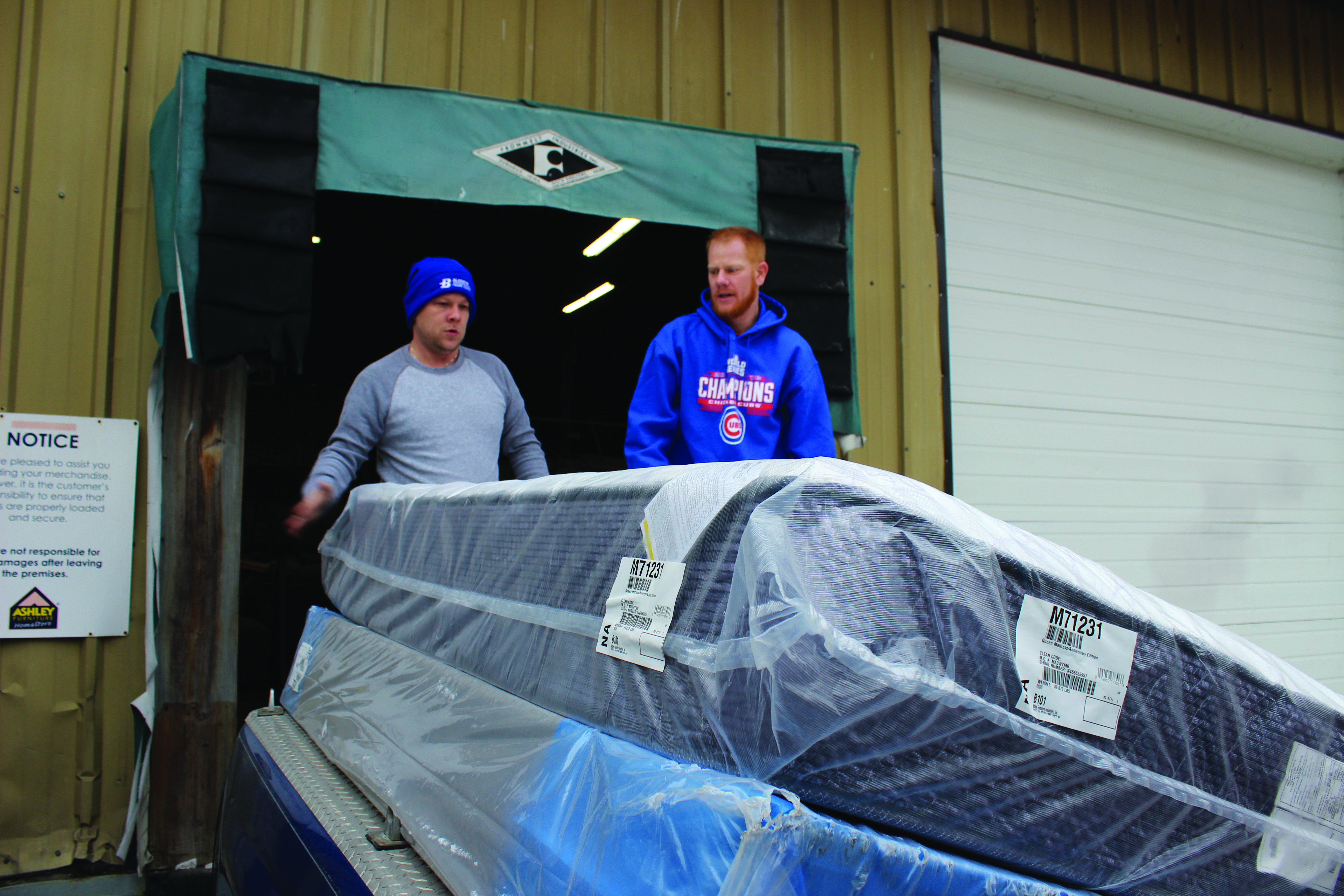 Dell Williams and Damion Dodd help deliver the mattress to Carol Dodds