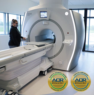 Woman standing by MRI machine.