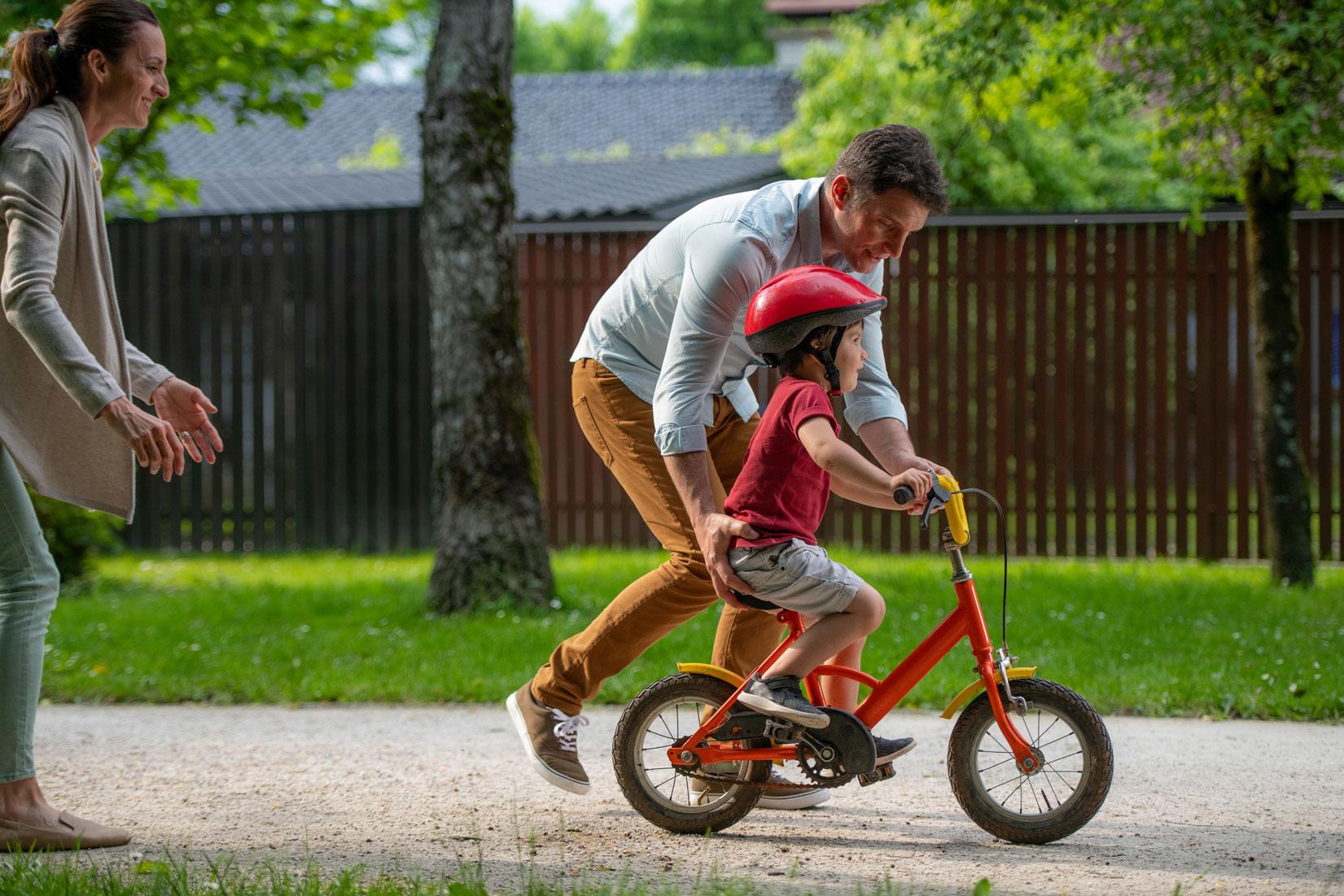 dad helping kid ride a bike